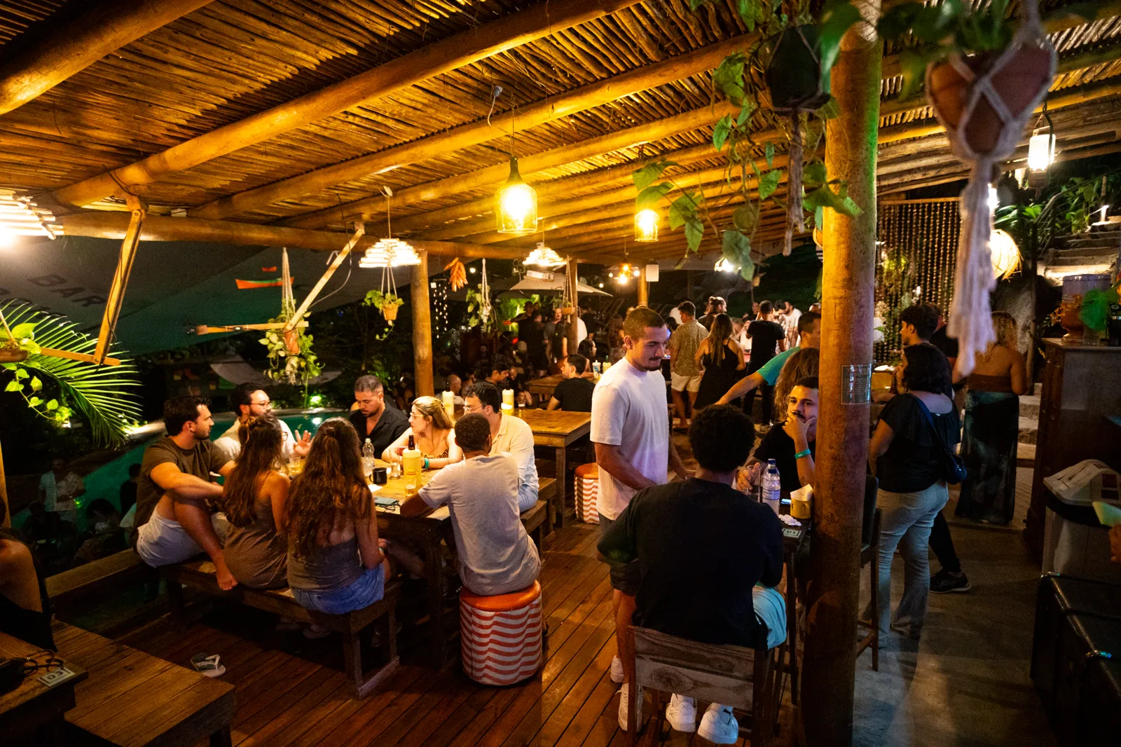 Mesas comunais no deck coberto do Floresta Bar à noite