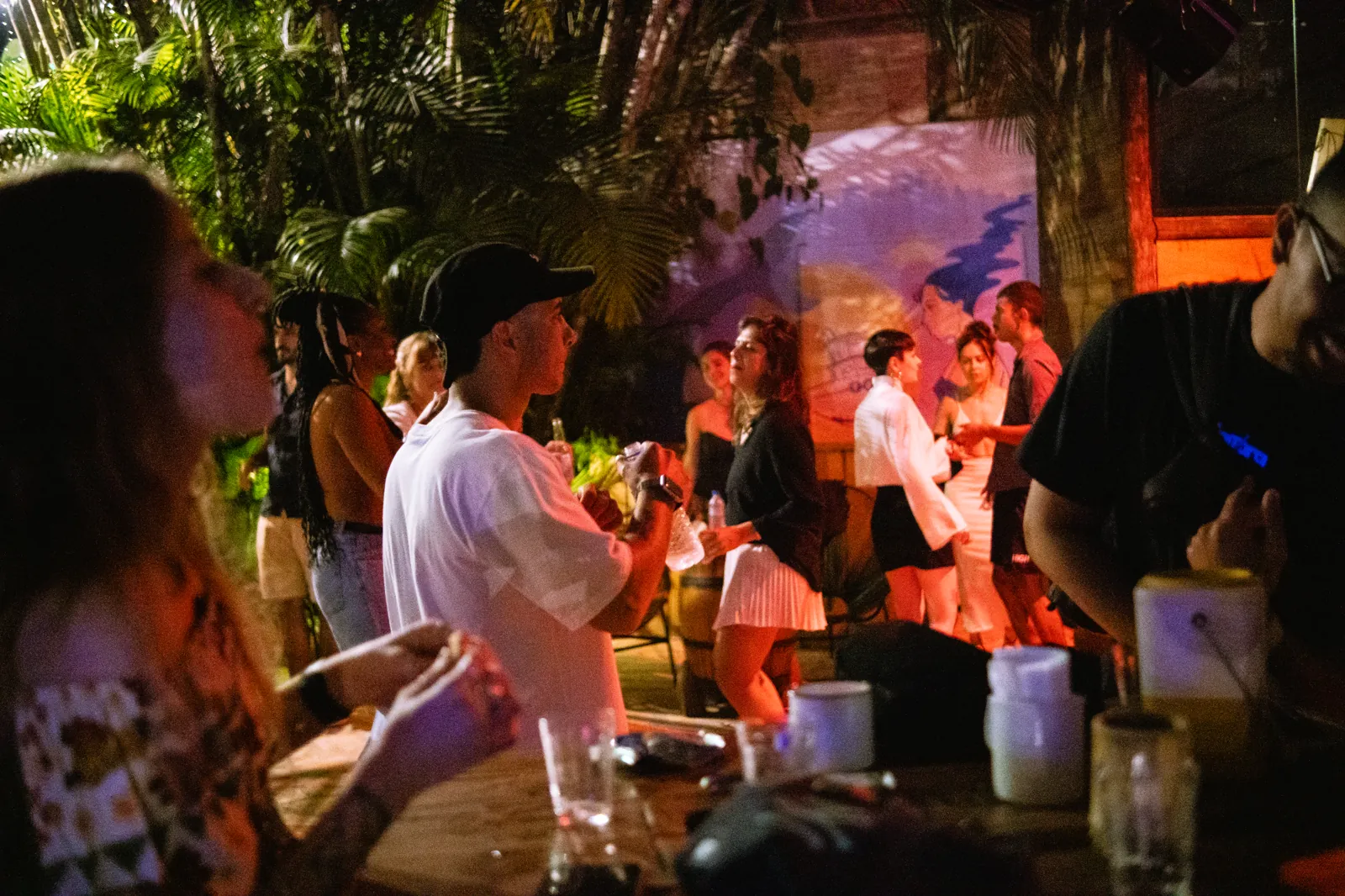 Público na festa noturna do Floresta Bar, sob projeção e luzes coloridas