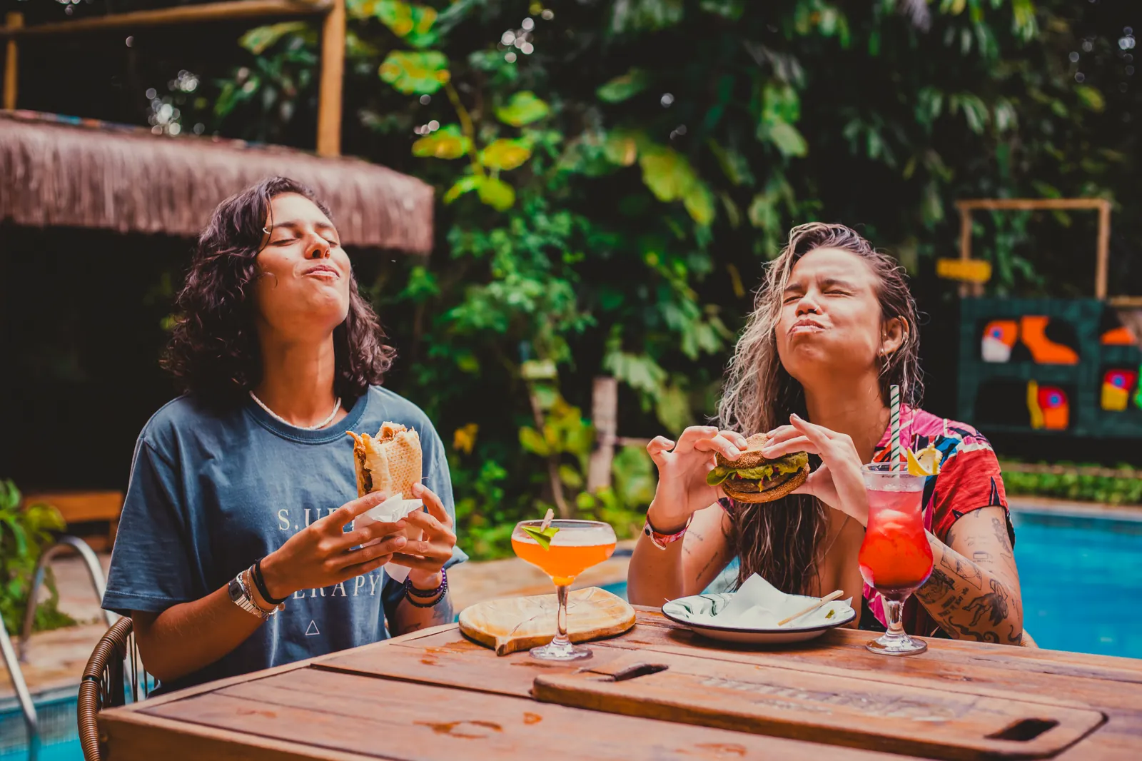 Amigas com hambúrguer, shawarma e drinks à beira da piscina no Floresta Bar