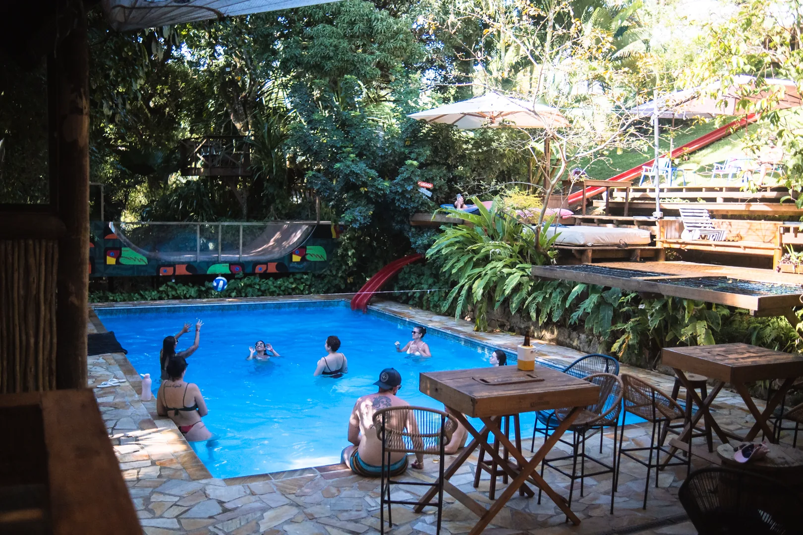 Hóspedes na piscina aquecida a 32°C do Hostel da Vila em Ilhabela, cercada de Mata Atlântica