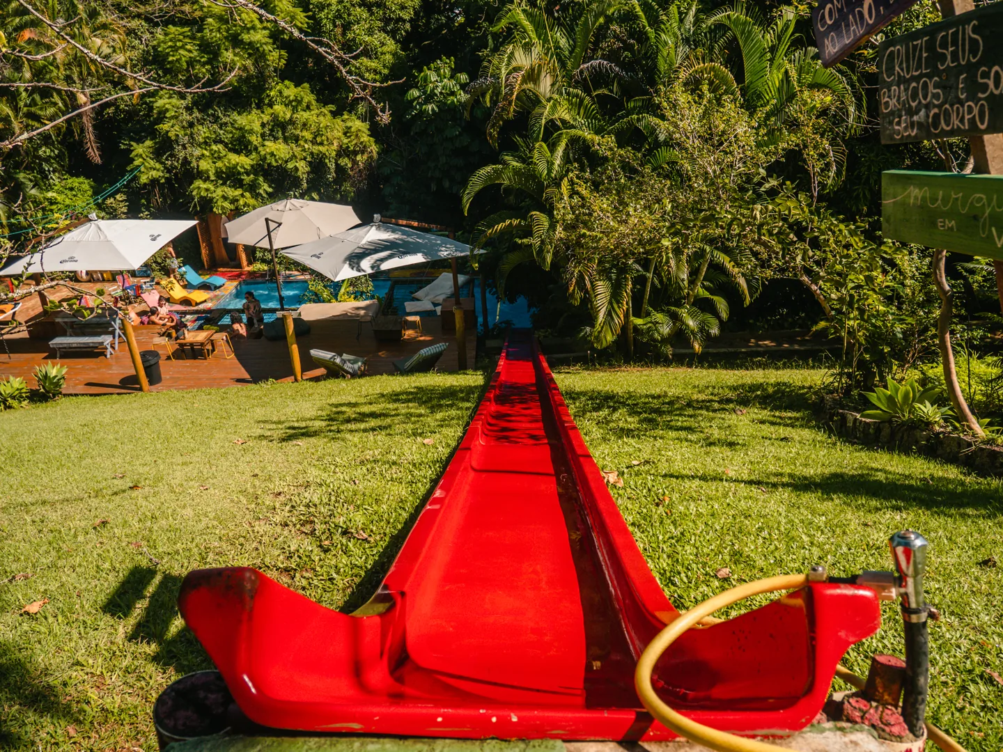 Tobogã vermelho de 20 metros que desce o gramado direto na piscina do Hostel da Vila em Ilhabela