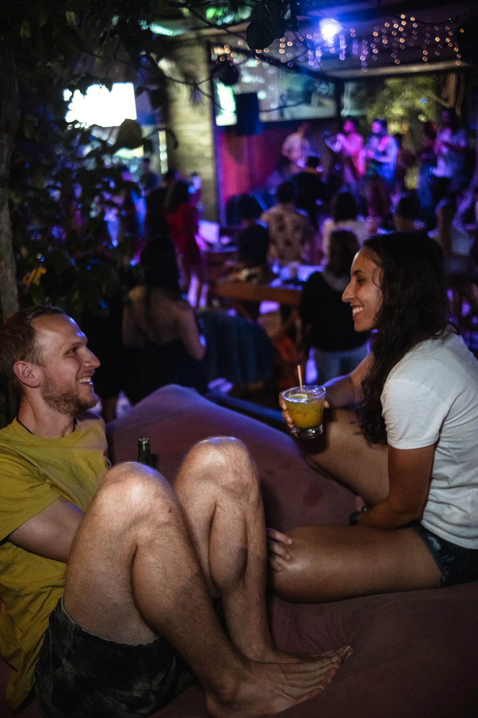 Hóspedes conversando com drinks no bar noturno do Hostel da Vila em Ilhabela