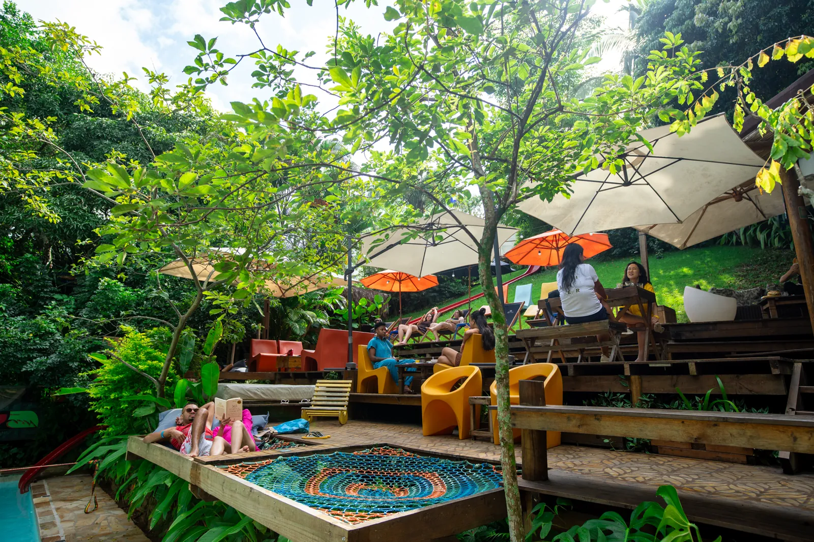 Área de lounge e jardim com redário e guarda-sóis no Hostel da Vila em Ilhabela