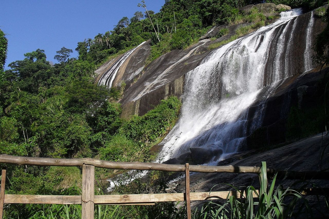 Queda d'água entre pedras escuras e mata fechada no Parque Estadual de Ilhabela