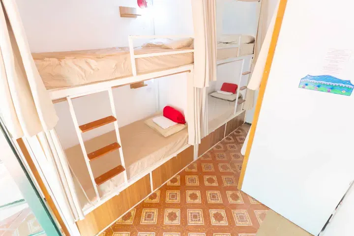 Beliches de dormitório com cortinas individuais e gavetões de madeira embaixo das camas