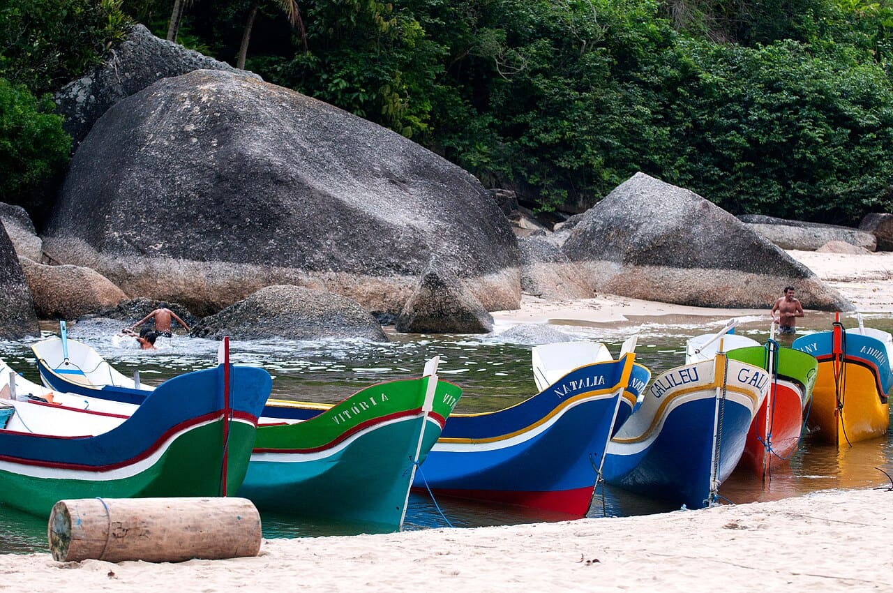 Canoas caiçaras de madeira alinhadas na areia da Praia do Bonete, com mar aberto ao fundo