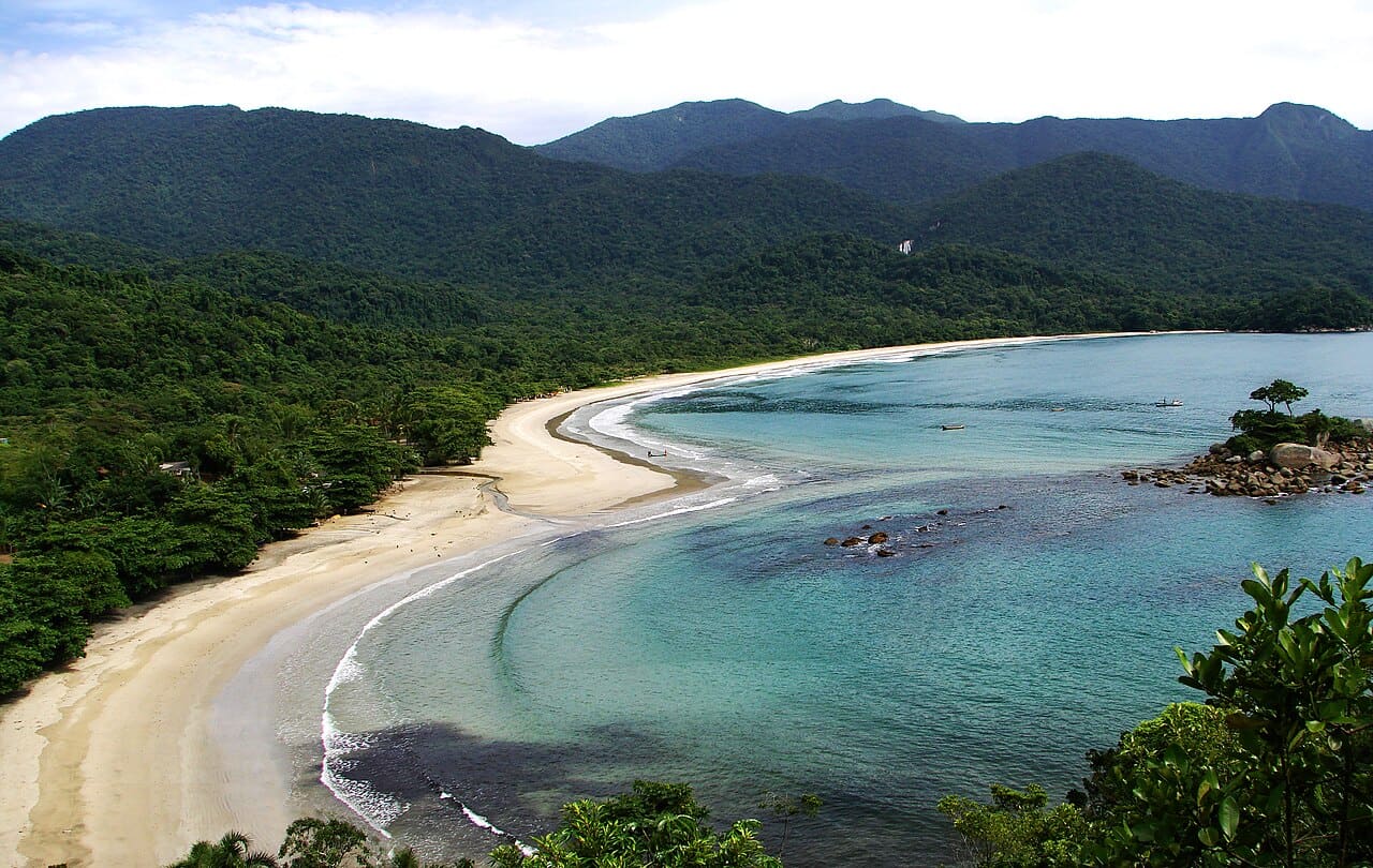 Baía de Castelhanos vista do alto, com a curva da praia desenhando um coração entre morros de Mata Atlântica