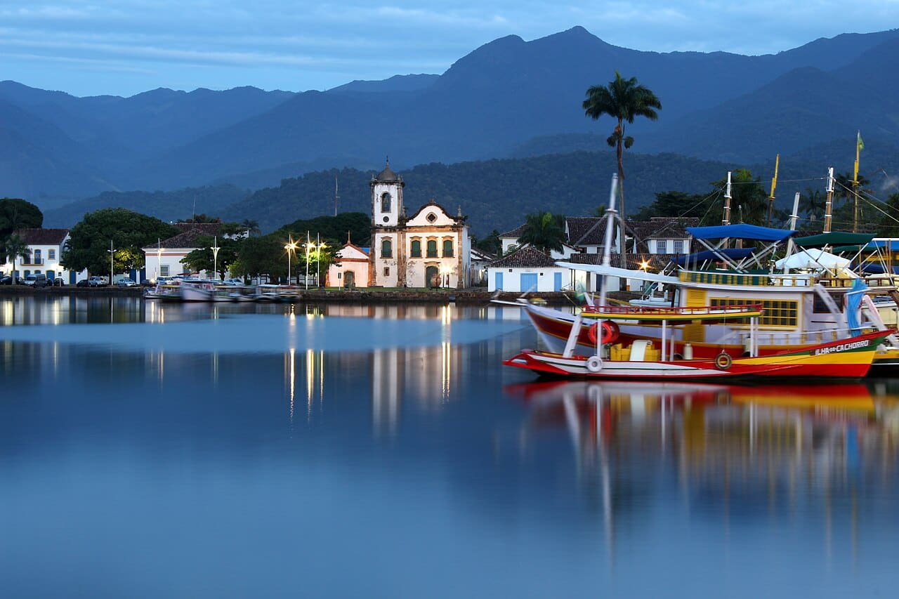 Centro histórico de Paraty visto do mar na hora azul, com a igreja de Santa Rita e barcos ancorados
